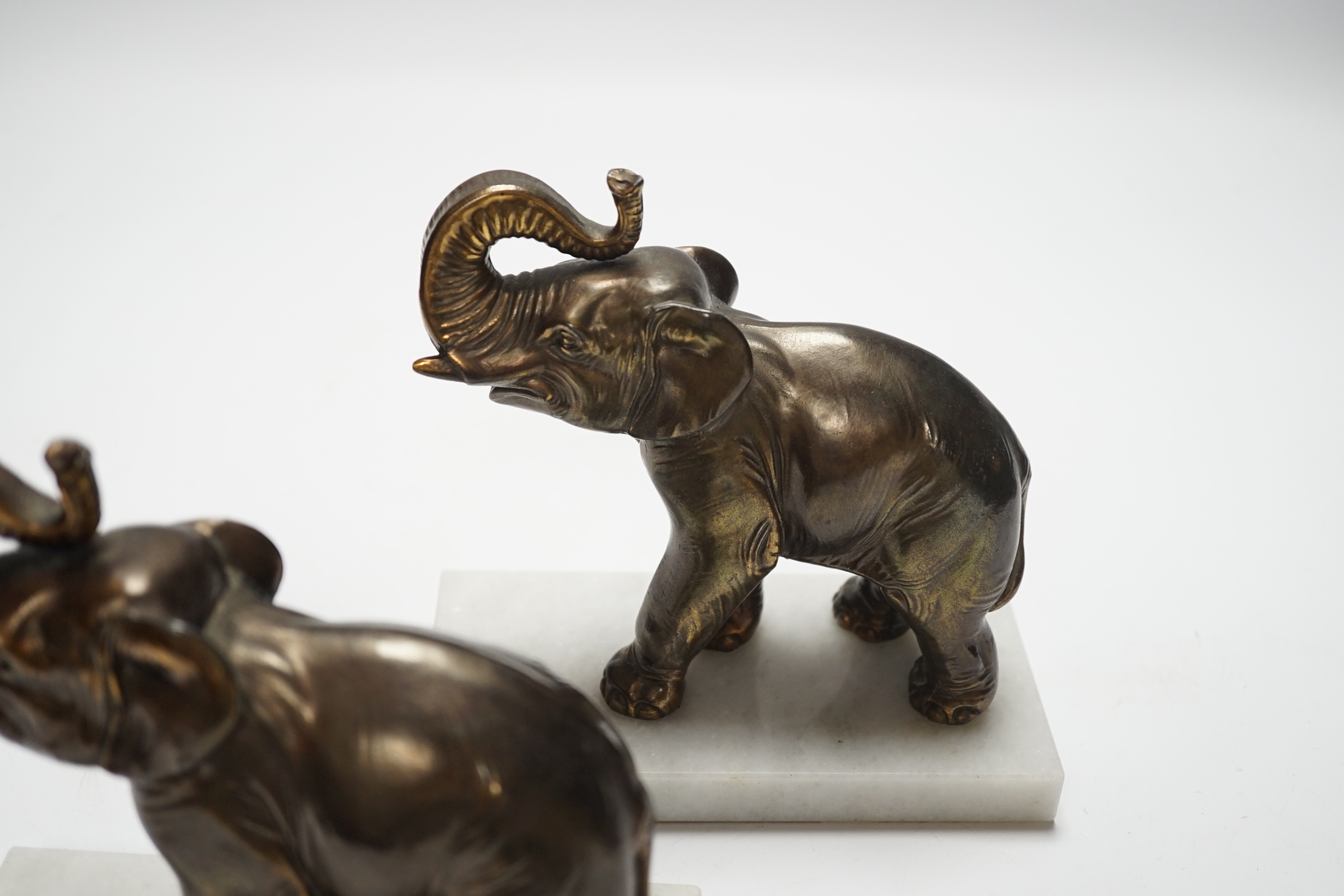 A pair of cast metal elephants on marble bases, 15.5cm high
